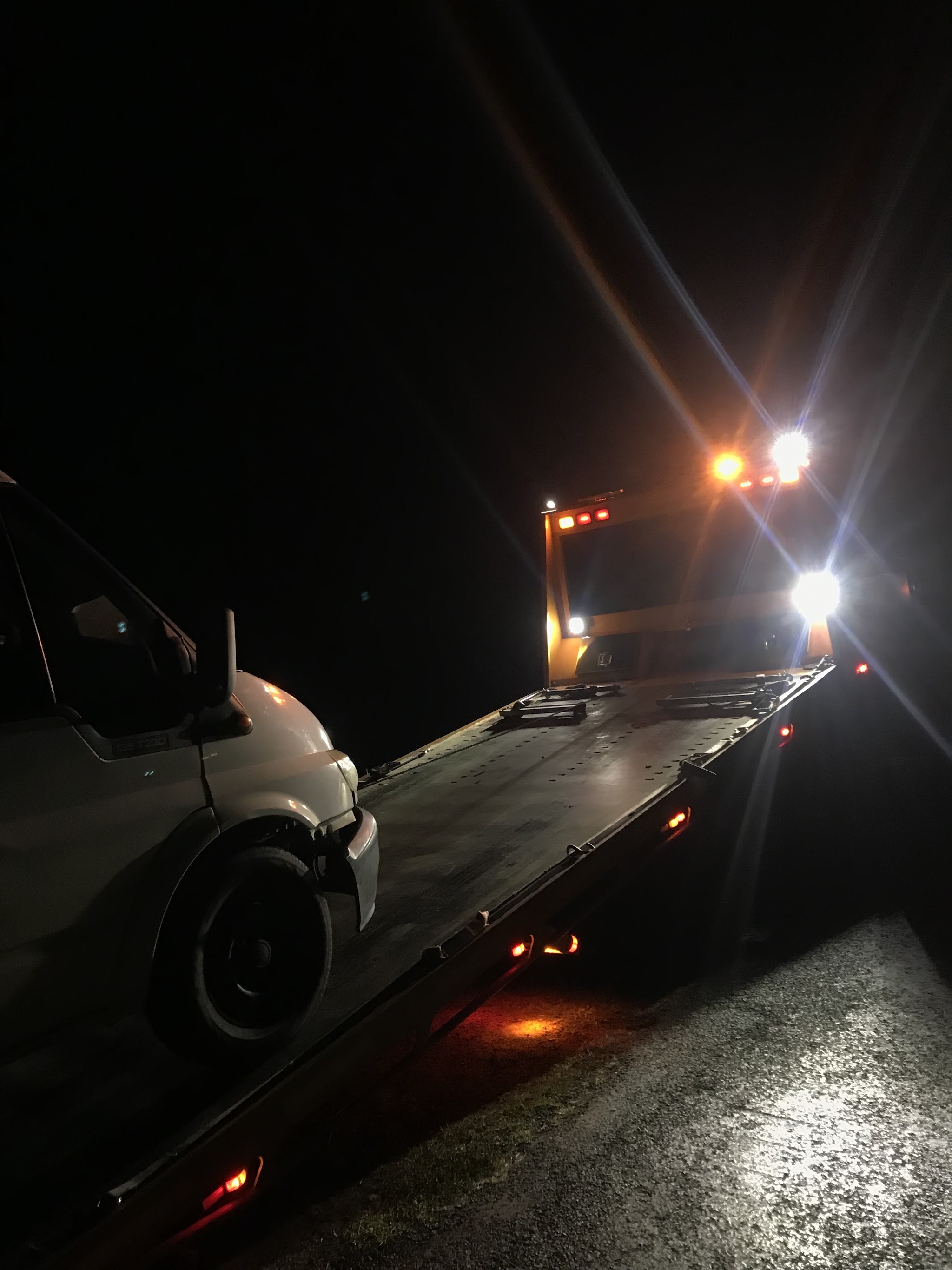Night time roadside recovery, work lights on and a van loaded on the tray